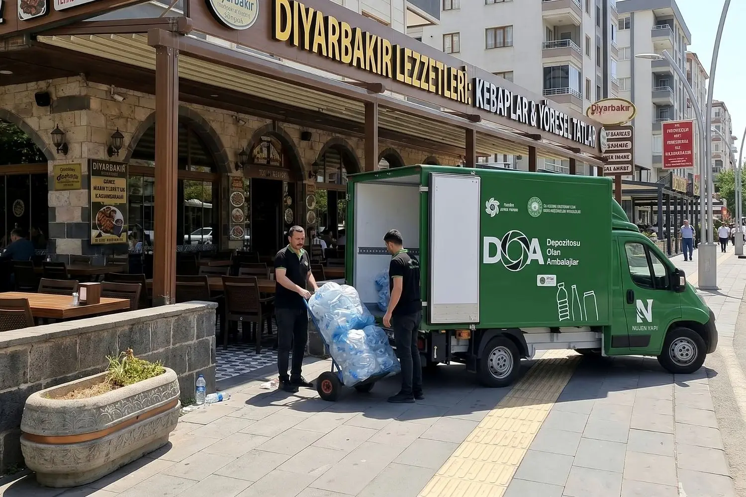 Diyarbakır'da bir restoranın önünde NUJEN ekibi, dolu toplama torbalarını el arabasıyla DOA logolu yeşil toplama aracına yüklüyor